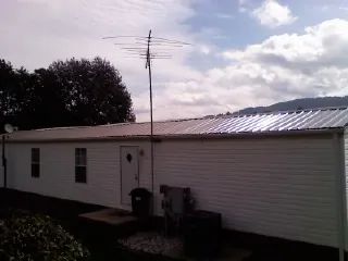 New metal roof on a single wide mobile home with a TV antenna in Laughlintown