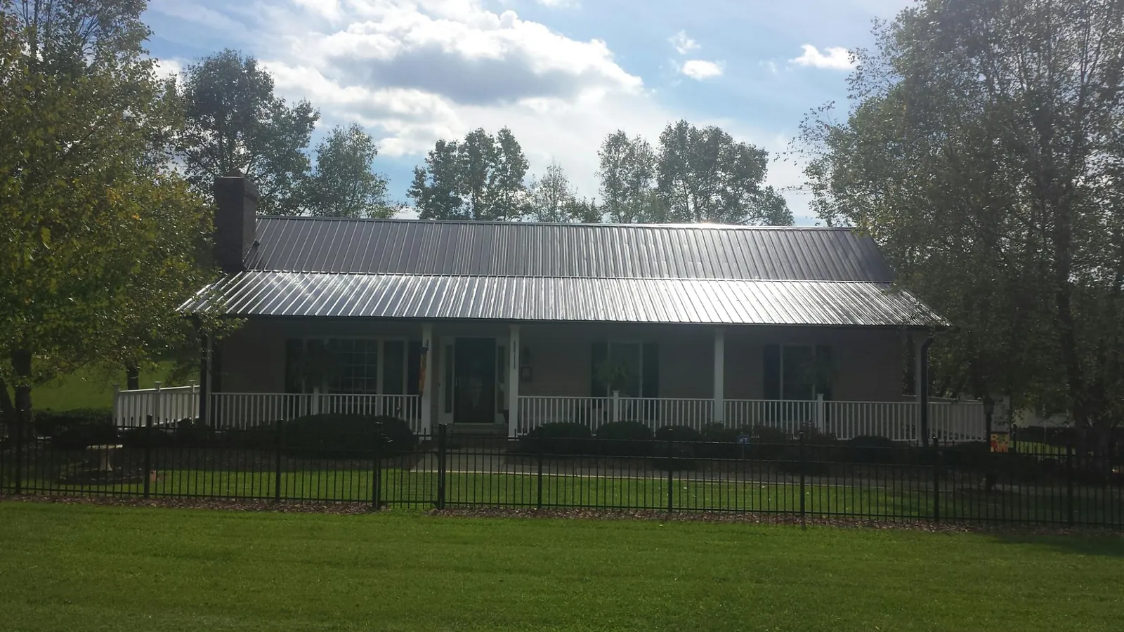 Gray metal roof on a brick ranch with a full width front porch — Gutter Guard Installation work by our crew in Laughlintown