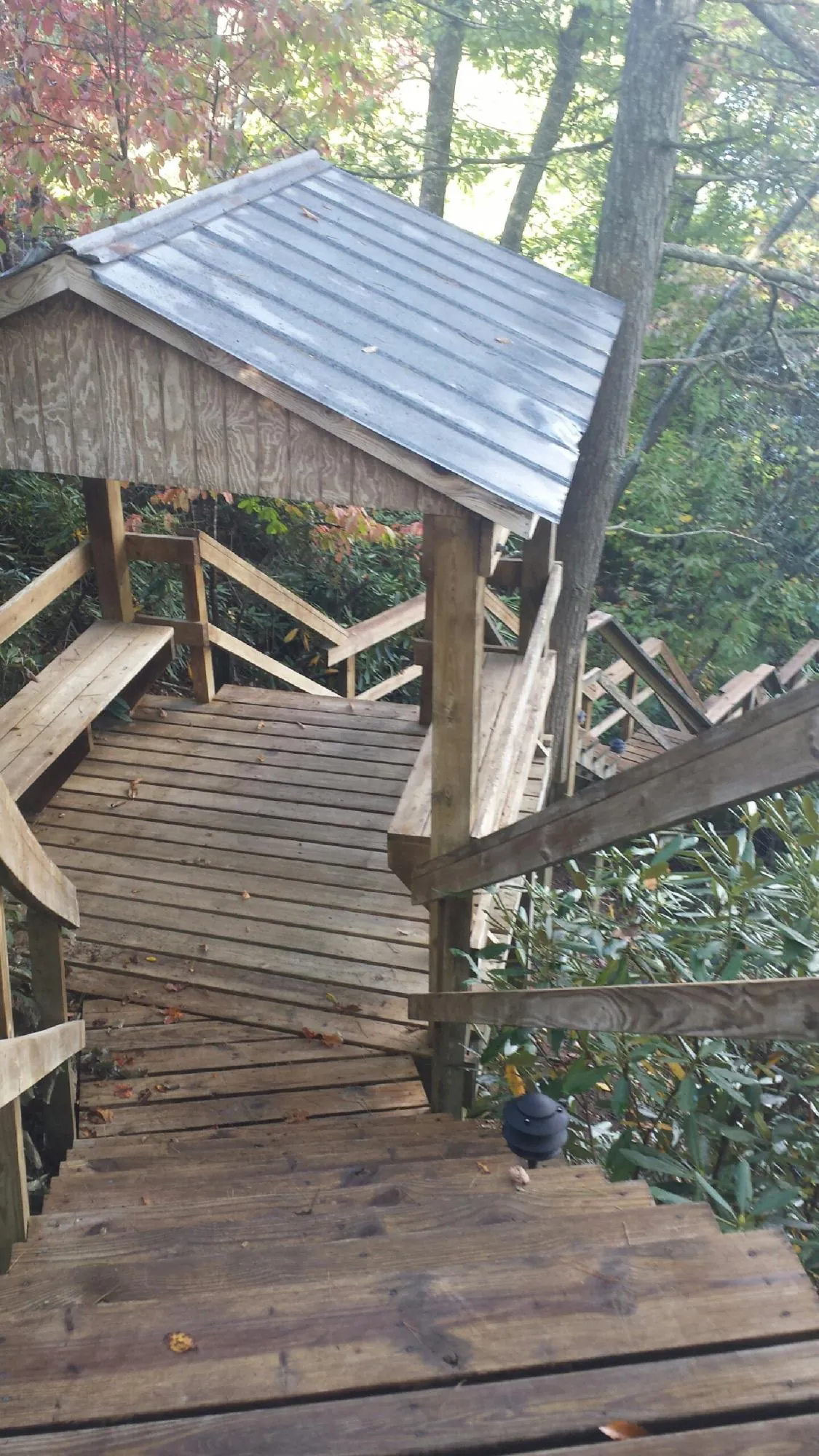 Metal roofed shelter over wooden steps on a wooded walkway — Skylight Repair & Installation work by our crew in Laughlintown