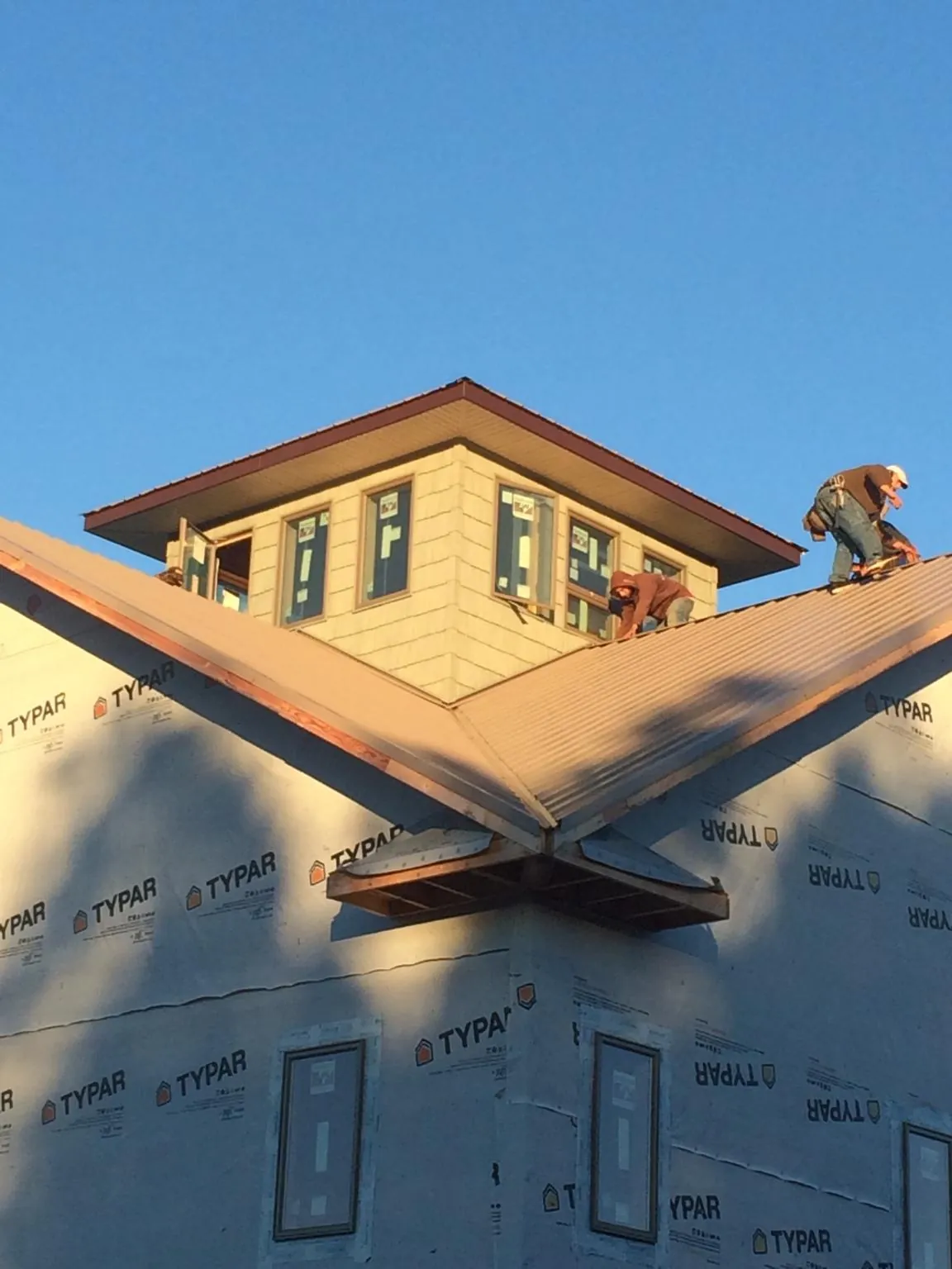 Roofers working around a rooftop cupola on a new metal roof at sunset — Roof Waterproofing in Laughlintown by Roofing Brothers